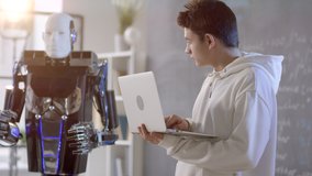 Caucasian student of senior classes making quantum robot clench and raise hands by turns controlling process on laptop - Powered by Shutterstock - Get 15% off with code: PIKWIZARD15