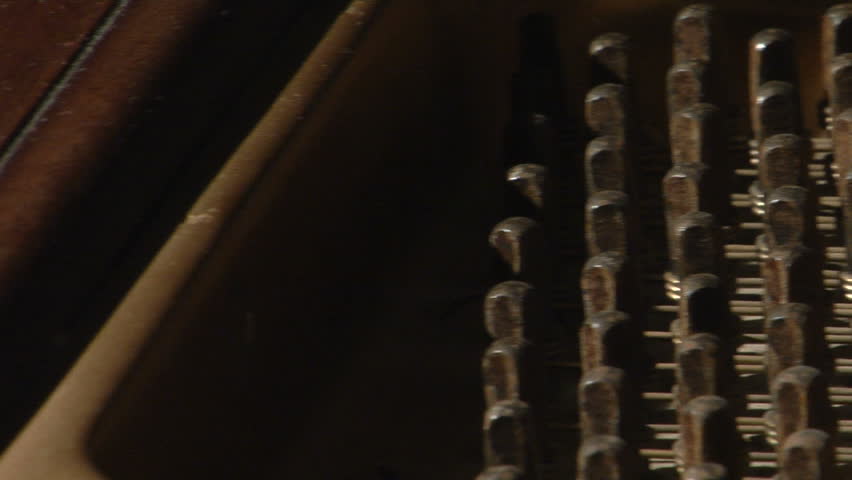 close up panning shot of the inside of a grand piano while it is playing.