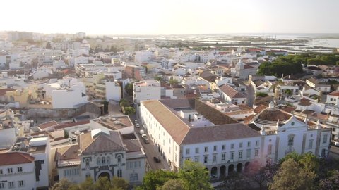 Amazing traditional European ocean side city of Faro with white buildings, during sunset and low tide, drone aerial