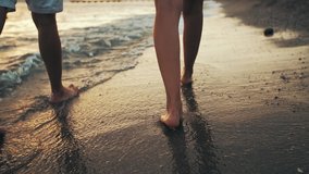 couple walks on the beach at sunset. The camera only takes the legs of the couple walking along the sea shore. - Powered by Shutterstock - Get 15% off with code: PIKWIZARD15
