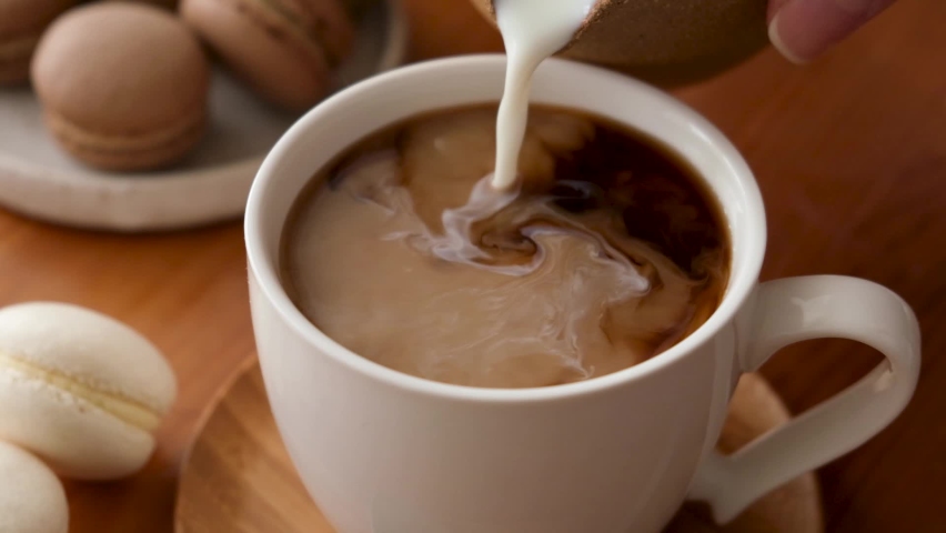 Adding coffee creamer into black coffee. Slow motion cream pouring in a cup of black coffee | Shutterstock HD Video #1061442259