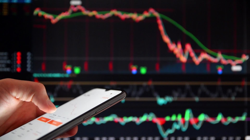 Investor analyzing stock market investments on a smartphone. Person trading stocks on a smartphone. Falling share prices at the stock exchange. Stock market crash. Trader at the stock exchange. | Shutterstock HD Video #1061442463