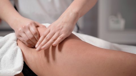 A woman masseur therapist makes a powerful anti-cellulite massage of the buttocks working tool to female client in a cosmetic clinic. Perfect skin fat burning beauty concept. Healthcare and medicine.