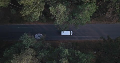 Flying, tracking the drone behind a white van, along a forest road with a bicycle path with a speed limit of 20 km. 스톡 비디오