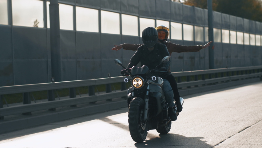 Close-up Happy Bikers in Helmets Riding on Motorcycle. Portrait of Caucasian Couple Man and Woman Driving Motorbike on Sunny Day Outdoors. Funny Carefree Girl Feels a Sense of Freedom. Slow mo Shot 4k Royalty-Free Stock Footage #1061446942