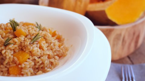 Pumpkin risotto, recipe with rice and pumpkin on rustic table with ingredients. Autumn and Halloween recipe.