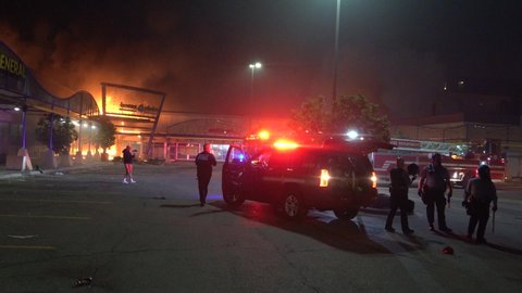 Minneapolis, Minnesota 5/29/2020 Police jump out of truck as they arrive at a burning strip mall during the riots following the death of George Floyd in Minneapolis, MN.