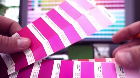 Graphic designer choosing colors from Pantone color guide palette. Catalog samples for printing proofing. Concept of color management in the print production process.