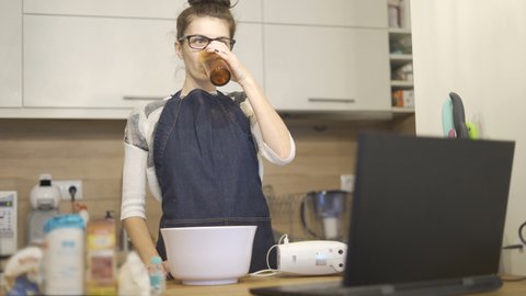 Beautiful woman drinking water whilist reading the meal recipe on laptop