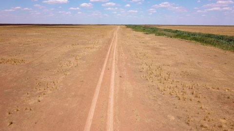 Fly over an empty dusty road via drone in desert or semi-desert region