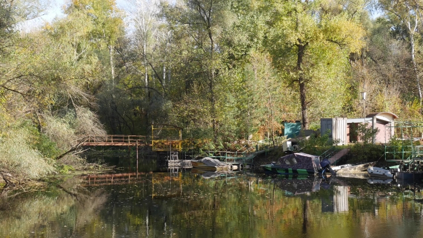 Quiet backwater against the backdrop of trees and a metal bridge near the shore.