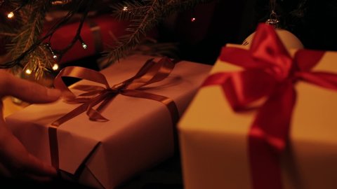 Taking pink gift under christmas tree. Beautiful presents under the Christmas tree. New Year interior. Christmas tree, happy holidays. New Year's gift box. Christmas spirit, holidays, celebration