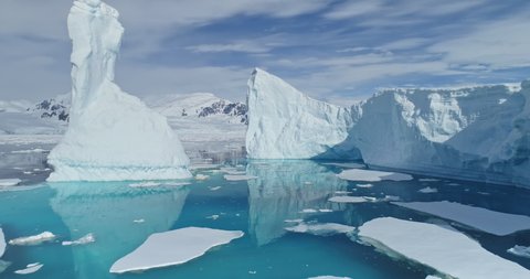 Tabular icebergs melt at turquoise ocean bay. Huge high ice glacier at polar nature environment. Arctic winter landscape at global warming problem. Desert white land of snow and ice drone shot.