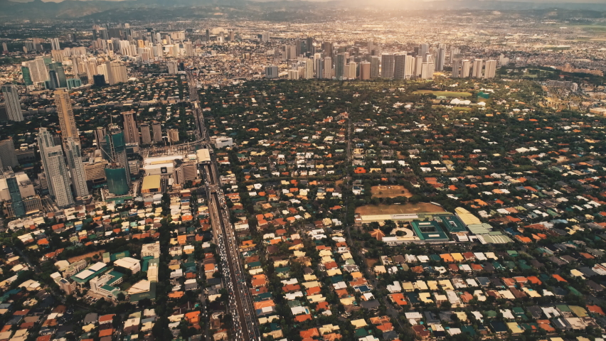 Slow motion sun metropolis city with streets, roads aerial. Downtown buildings, skyscrapers at summer sunny day. Cinematic cityscape of Manila town, Philippines, Asia. Birds-eye drone shot