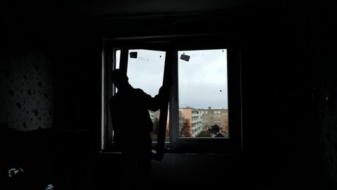 Silhouettes of builders install plastic windows in the house.