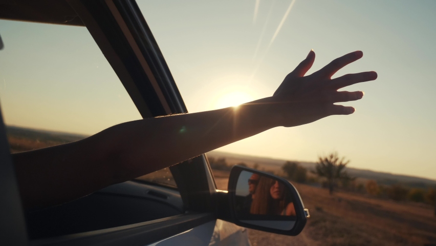 Free girl hand out of the window rides a car wind in the face. concept car travel on the road. girl stretches her hand out of the car window sun glare sunset. driver hand out of the window movement | Shutterstock HD Video #1061477728