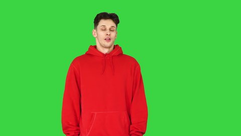 Young caucasian man dancer in red hoody talking to camera on a Green Screen, Chroma Key.