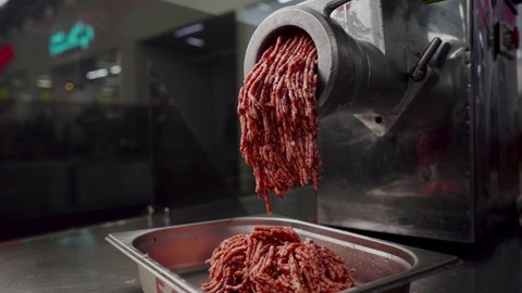 Super slow motion making minced meat in an electric meat grinder from fresh beef at the meat processing plant. mincer machine with fresh chopped meat.