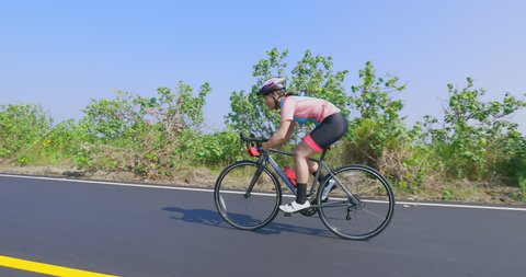 Side view of asian young woman wearing helmet is riding a bicycle on the road