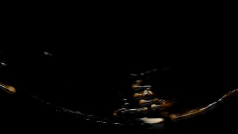 Dark sparkling liquid pouring splashing in slow motion on black background, drinks concept. Dark soda, dark beer, kvass, lager, black Ipa, brown Ale, Stout, Porter, Dunkel, Bock, Dunkelweizen