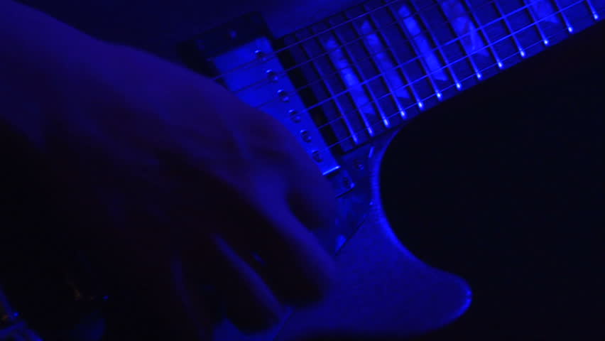 close up shot of a man playing a guitar at a rock concert at a popular club on