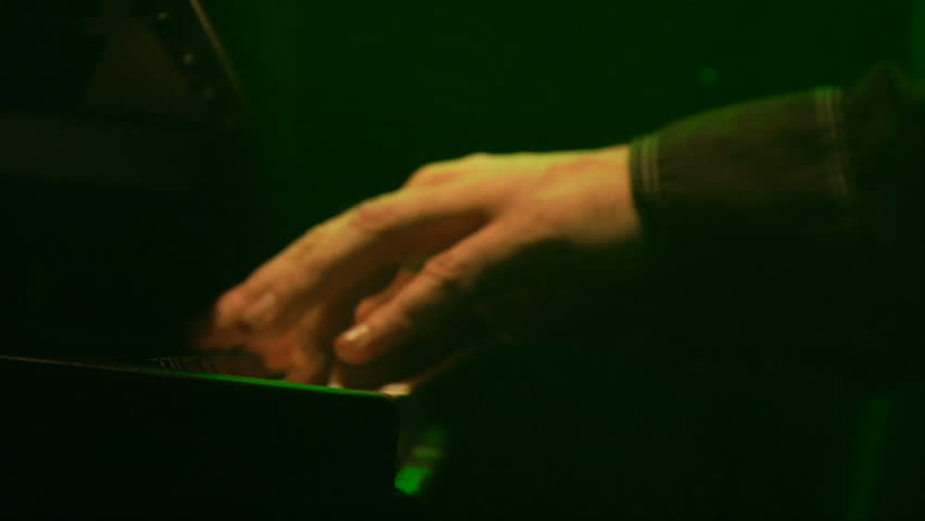 close up shot of a hand playing a keyboard in at a rock n roll concert.