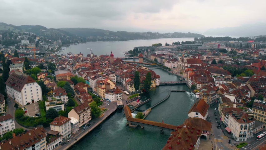 Aerial view overlooking the Reuss river the downtown of Luzern city, on a cloudy, summer day, in Lucerne, Switzerland - reverse, drone shot