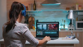 Video editor wearing headset and working from home at digital project sitting in the kitchen. Videographer editing audio film montage on professional laptop sitting on desk in midnight - Powered by Shutterstock - Get 15% off with code: PIKWIZARD15