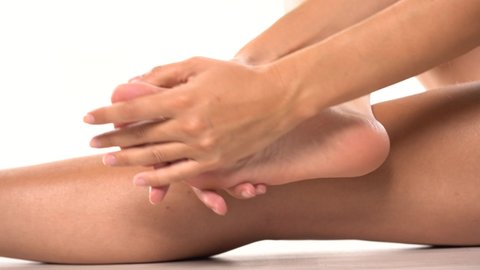 woman massaging her tired feet on a white background