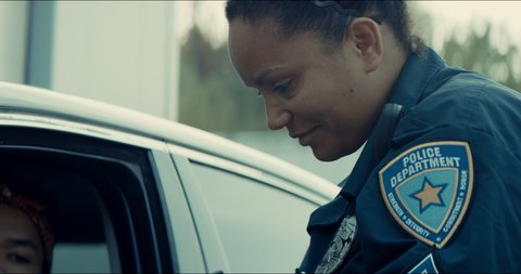 African-American black driver getting a ticket from mixed-raced female police officer. Shot on RED cinema camera with 2x Anamorphic lens