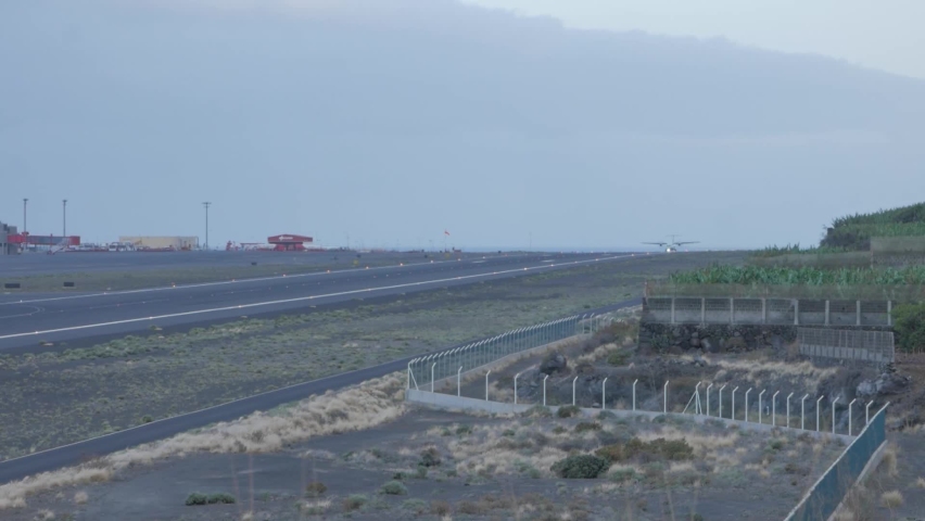 A shot of a twin-engine propeller passengers plane tsking off from a small airport with one only lane. it is the La Palma airport, located in the Canary Islands.