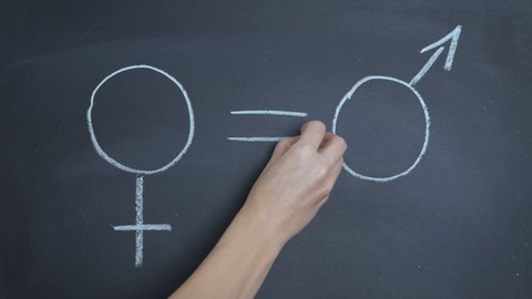 Equality in the school. A view of a woman write an equality between man and female on blackboard.