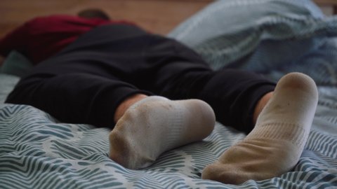 man in dirty white socks is lying on the bed