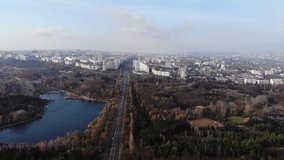 Aerial view with drone over a city, House located in the middle of the park. Beautifully protected lake. Flying birds. The city of Chisinau seen from above. Beautiful landscape