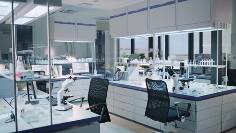 Modern Empty Biological Applied Science Laboratory with Technological Microscopes, Glass Test Tubes, Micropipettes and Desktop Computers and Displays. PC's are Running Sophisticated DNA Calculations.