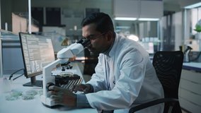 Medical Research Scientist Conducts DNA Experiments Under a Microscope and Writes Results on Desktop Computer in a Biological Science Laboratory. Diverse Multiethnic Lab with Engineers in White Coats. - Powered by Shutterstock - Get 15% off with code: PIKWIZARD15