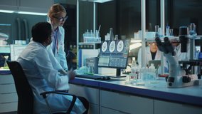 Female Research Scientist Has a Conversation with Bioengineer About the Effects of Different Pharmaceutical Drugs on Brain. They Look at Computer Software Visualization in a Modern Science Laboratory. - Powered by Shutterstock - Get 15% off with code: PIKWIZARD15