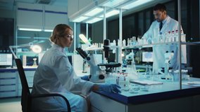 Medical Research Scientist Looks at Biological Samples Under Digital Microscope in Applied Science Laboratory. Beautiful Caucasian Lab Engineer in White Coat Working on Vaccine and Medicine. - Powered by Shutterstock - Get 15% off with code: PIKWIZARD15