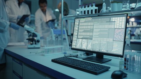 Desktop Computer is Running Software Analysis while Performing Virus Extraction Experiments. Sophisticated Programming is Visible on the Display with Code and DNA Samples. Medical Research Laboratory.