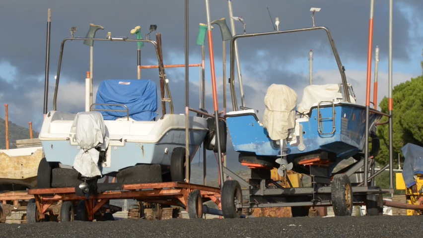 two motor boats put out of the water on carts on the beach