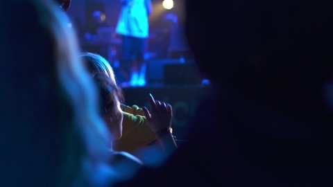 Crowd of fans of the musical band applauding in a nightclub during live performance. Rock concerts where people dancing and adore their idols. Concept of parties and night lifestyle