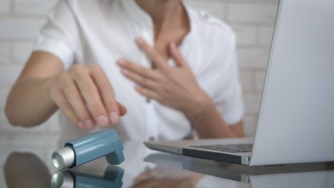 Asthma in the office. A woman in the workplace is choking from an asthma attack.