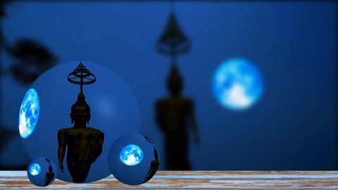 Reflection of blue hunter moon moving on night sky and silhouette buddha on crystal ball glass