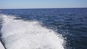 Motor boat goes on the sea, waves from the back of the speedboat. Video of waves, splashes from a motor boat going on the sea. Beautiful sea wave on a Sunny day. slow-motion