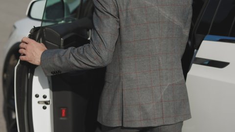 Businessman getting in of car and walking to office. Unrecognizable businessman commuting to work. Confident guy in suit being on his way to job.