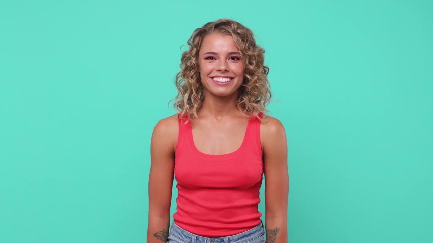 Shocked surprised young blonde woman 20s years old in pink tank top posing isolated on blue turquoise background studio. People lifestyle concept. Looking camera spreading hands put palms on cheeks Royalty-Free Stock Footage #1061525191