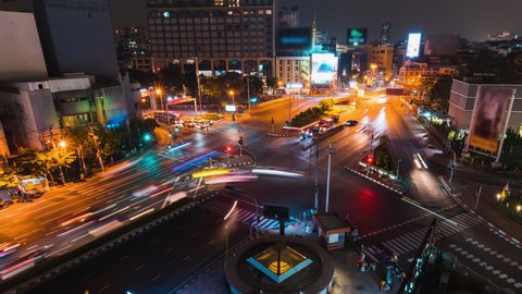 Time-lapse of car traffic transportation on road intersection junction and billboard advertisement at night in Bangkok Thailand. Urban transport lifestyle, Asian city life. High angle cityscape view