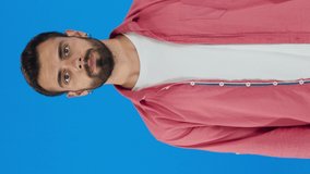 Young handsome man with beard on blue background makes stop sign with palms. Warning expression with negative and serious gesture on face.