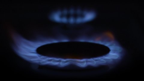 Close up of a gas stove firing up on the oven with another one already burning in background - long take in slow motion