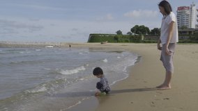 4K Video Mother and 3 years old asian kid playing on the beach. Background for family vacation and recreation.